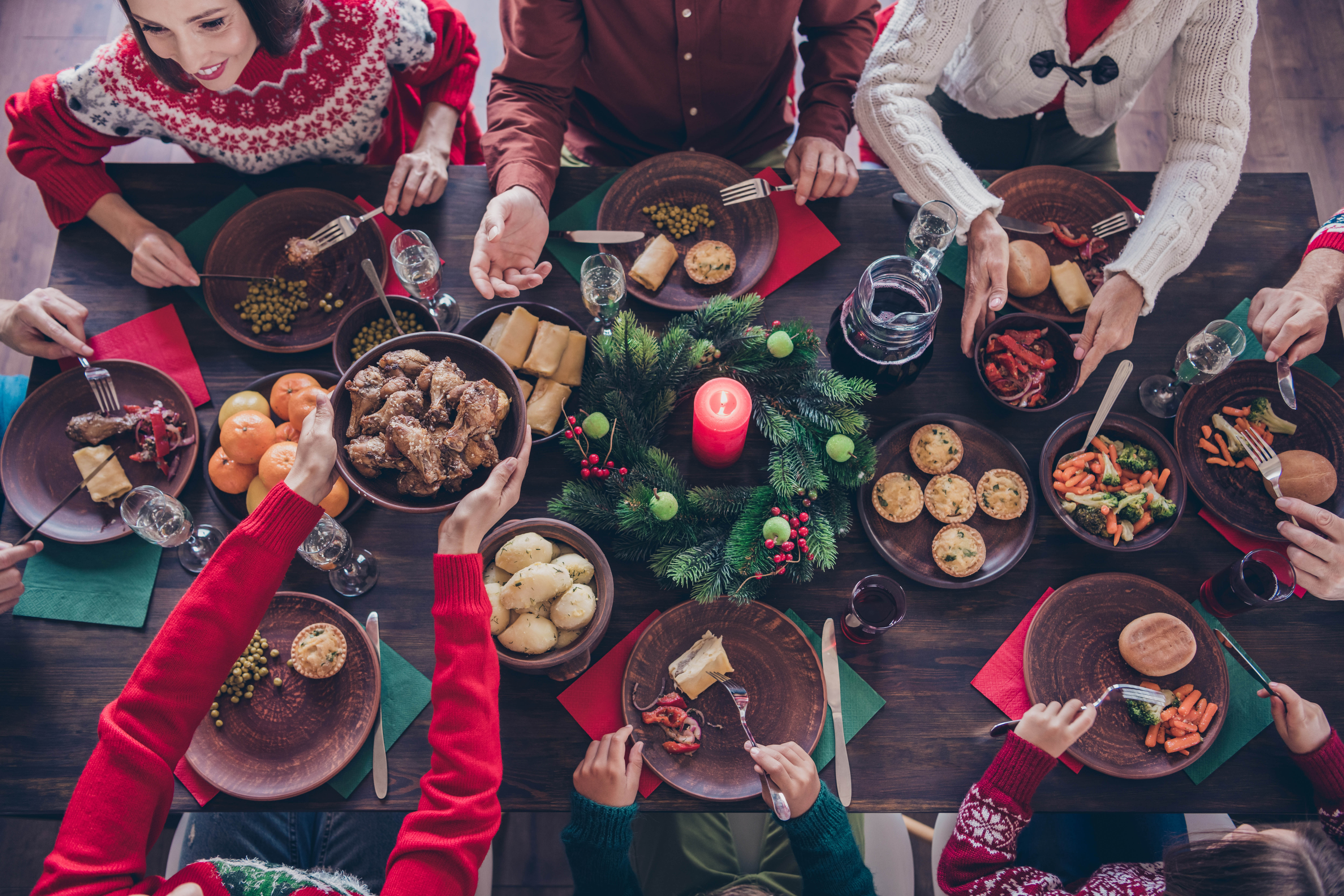 Overhead shot of a Christmas dinner table with everyone conversing and eating Overhead shot of a Christmas dinner table with everyone conversing and eating